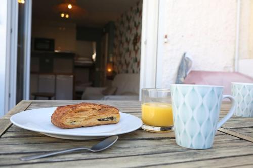 einen Tisch mit einem Teller Brot und einem Glas Orangensaft in der Unterkunft Appartement Lavande YourHostHelper in Saint-Cyr-sur-Mer