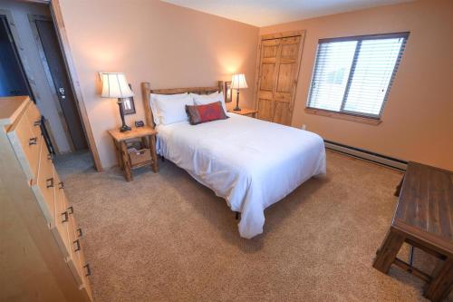 a bedroom with a large white bed and a window at Trapper Condo Unit 5 in West Yellowstone