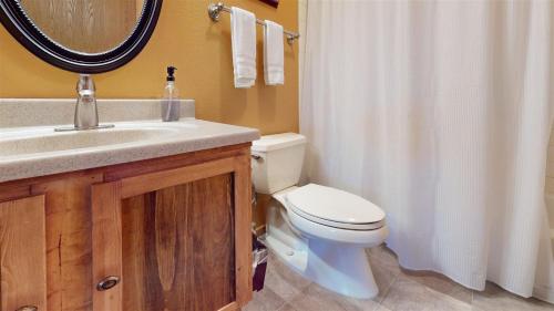 a bathroom with a toilet and a sink and a mirror at Trapper Condo Unit 5 in West Yellowstone