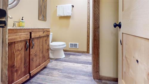 a bathroom with a toilet and a sink with a wooden cabinet at Trapper Condo Unit 5 in West Yellowstone