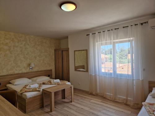 a bedroom with a bed and a table and a window at Apartment and Rooms Amenka in Novalja