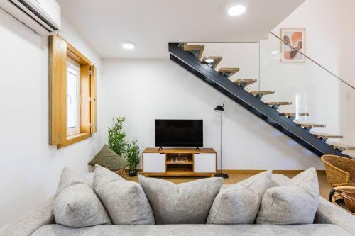 ein Wohnzimmer mit einem Sofa und einer Treppe in der Unterkunft Inner Center Porto in Porto