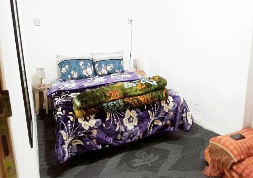a bed with a purple comforter and pillows at 1A private room in a shared house for surfers in Safi