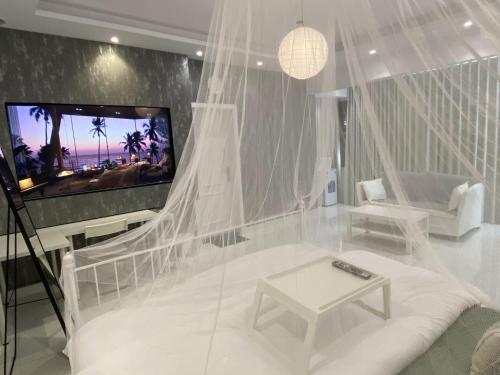 a white living room with a tv and a couch at Lovely Suite in Jeddah
