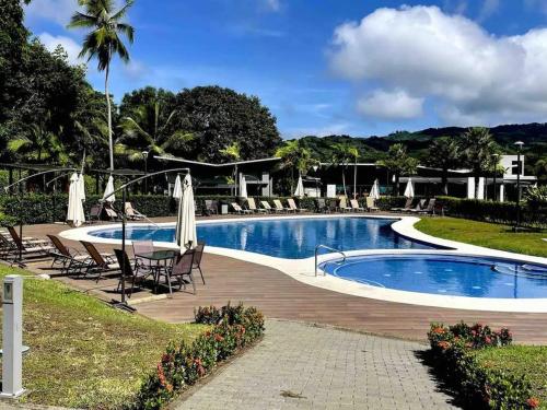 a pool at a resort with chairs and umbrellas at Jaco Beach Villa Arenas Condo in Jacó