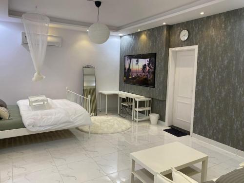 Habitación con cama, mesas y TV. en Lovely Suite en Yeda
