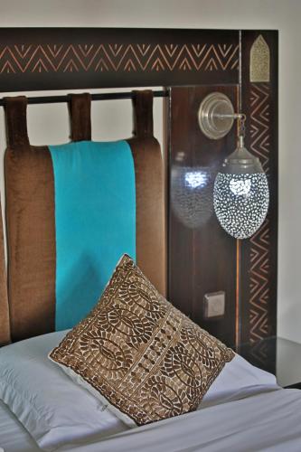 a bed with a brown pillow and a lamp at Riad Dar L'Oussia & SPA in Essaouira