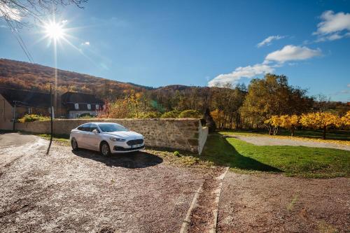 a white car parked in a gravel parking lot at Moulin Renaudiots - Maison d'hôtes in Autun