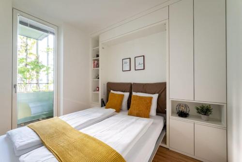 a white bedroom with a large bed with yellow pillows at HM • New Studio by WU & Messe in Vienna