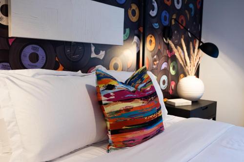 a white bed with a colorful pillow on it at Hyve - Riff n Roll - Walk to Broadway in Nashville