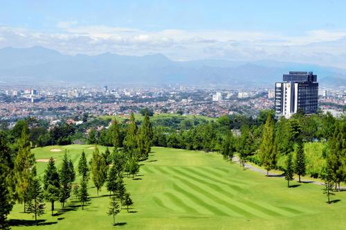 a golf course with trees and a city in the background at InterContinental Bandung Dago Pakar by IHG in Bandung