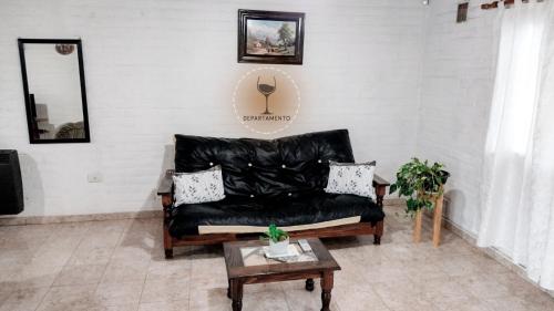 a living room with a black leather couch and a table at Malbec Departamentos in Maipú