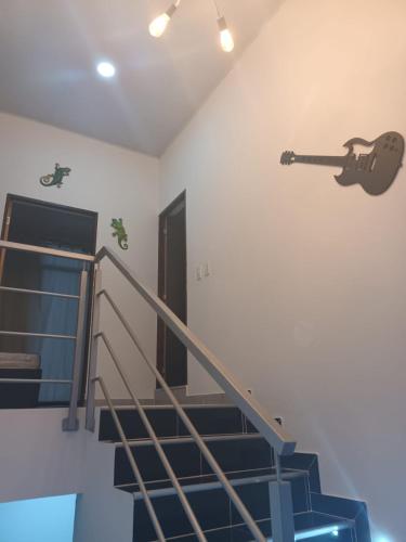 a guitar on the wall next to a staircase at Villa con piscina privada y zona bbq en condominio in Carmen de Apicalá
