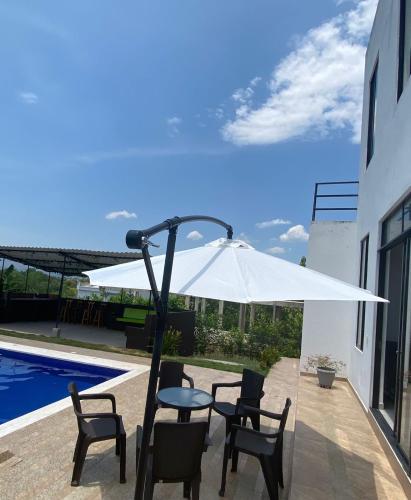a white umbrella sitting on a patio next to a pool at Villa con piscina privada y zona bbq en condominio in Carmen de Apicalá