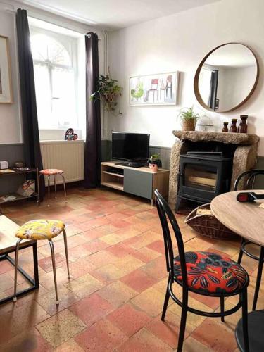 een woonkamer met een tafel en stoelen en een open haard bij Charmante Maisonette à Arçonnay (72) in Arçonnay