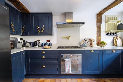 a kitchen with blue cabinets and a stove at Huge & Deluxe 600 Year Old Essex Manor House in Saffron Walden