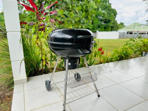 a charcoal grill on a metal stand on a patio at Promo ! La Villa Armony, Havre de Paix avec Jardin Privé ! in Lamentin