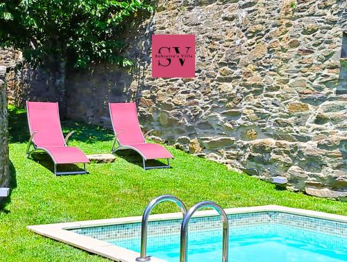 two pink chairs and a swimming pool with a sign at Sobreiro's Villa in Douro Valley in Mesão Frio