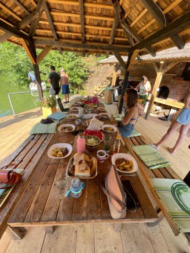 a long wooden table with plates of food on it at Brvnare na jezeru Marinkovići in Bajina Bašta