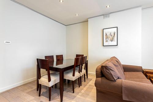 a dining room with a table and chairs and a couch at Cosy Kensington Two Bedroom Flat in London