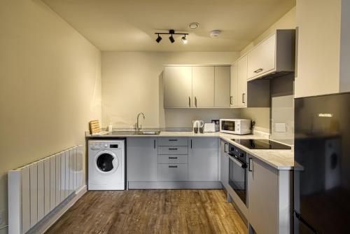 a kitchen with white cabinets and a washer and dryer at Renaissance House - 16 Picturesque Apartments in Southport in Southport