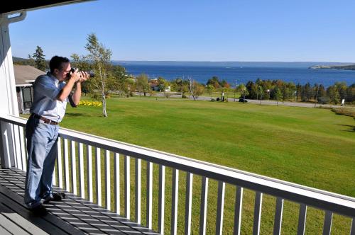 
a man on a balcony looking at the water at Silver Dart Lodge in Baddeck
