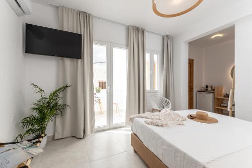 a white bedroom with a bed and a large window at Golden Bird's in Naxos Chora