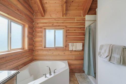 baño con bañera blanca y paredes de madera en Splendor Valley Farms: Huge Log Cabin w/ Game Room, en Kamas