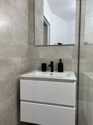 ein Badezimmer mit einem weißen Waschbecken und einem Spiegel in der Unterkunft A&A’s crib in Alba Iulia