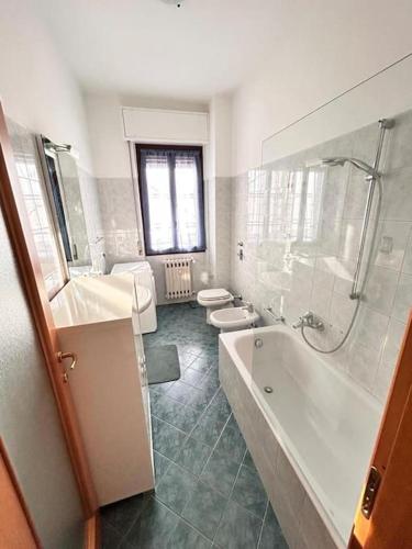 a bathroom with a tub and a shower and two toilets at Soleo guesthouse in Monza