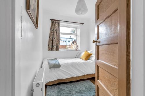 um pequeno quarto com uma cama e uma janela em Sunny 2BD London Maisonette with Garden for 3 em Londres