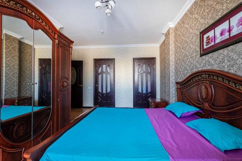 アスタナにあるТреумф Астаныのベッドルーム1室(大型木製ベッド1台、青いシーツ付)