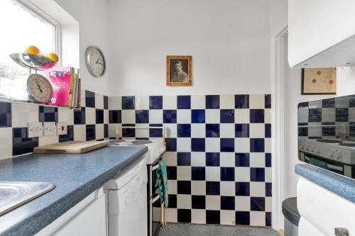 una cocina con azulejos blancos y negros a cuadros en Sunny 2BD London Maisonette with Garden for 3, en Londres