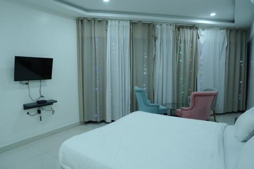 een slaapkamer met een bed en 2 stoelen en een televisie bij 12 degree comforts in Bangalore
