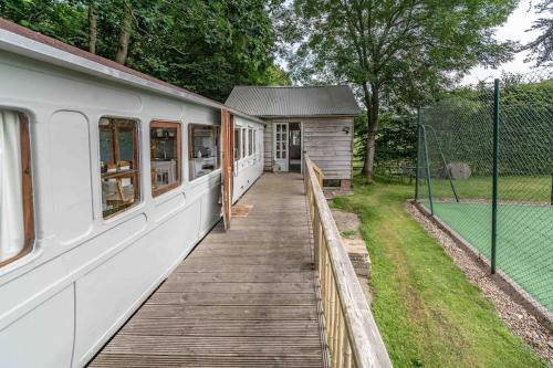 a train on a wooden walkway next to a building at Railway Carriage accommodation with tennis court! in Walberton