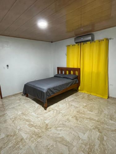 a bedroom with a bed and a yellow curtain at KingFish in Colón