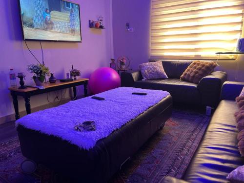 ein lila Wohnzimmer mit einem Sofa und einem Tisch in der Unterkunft SKY Havens Apartments in Accra