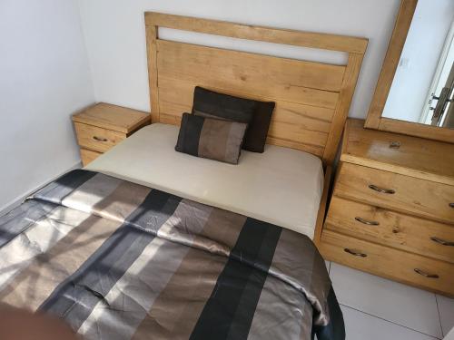 a bedroom with a bed with a wooden headboard at Cozy 2 Bedroom Bungalow. in Freetown
