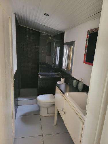 a bathroom with a toilet and a tub and a sink at Cozy 2 Bedroom Bungalow. in Freetown