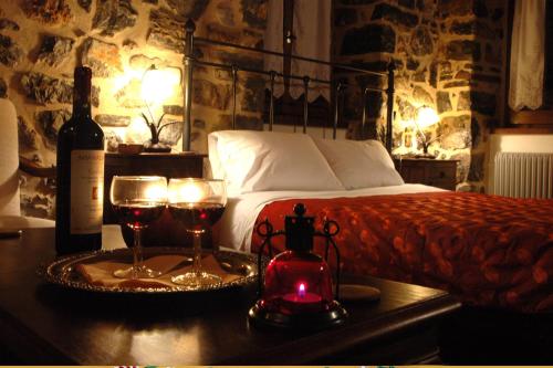 a bedroom with a bed and two glasses of wine at Archontiko Nikolopoulou in Vitina
