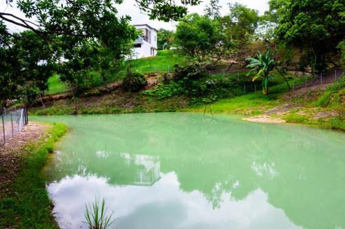 a pond of green water with a house in the background at Casas Campestres Los Miradores de Fruworld in Carmen de Apicalá