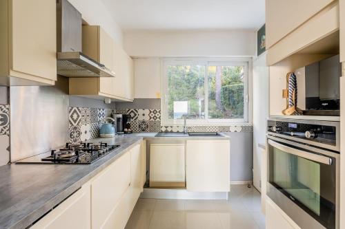 une cuisine avec des armoires blanches et une fenêtre dans l'établissement Le Super Bestouan par Dodo à Cassis, à Cassis