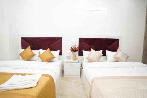 2 łóżka w pokoju z białymi i złotymi poduszkami w obiekcie Hotel Diamond Stay, Nizamuddin Railway Station w Nowym Delhi