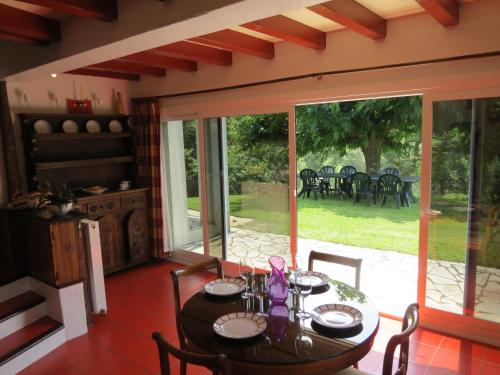 une salle à manger avec une table et une grande fenêtre en verre dans l'établissement Maison typique Basque en pleine campagne, à Saint-Pée-sur-Nivelle