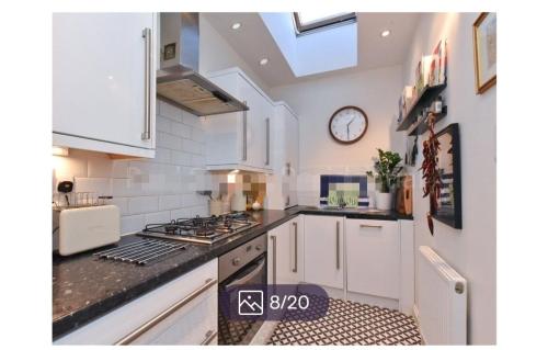 a kitchen with white cabinets and a clock on the wall at Veronika’s in London