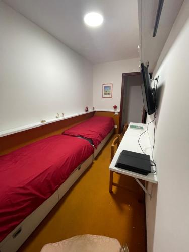 1 dormitorio con cama roja y mesa con TV en Appartamento per Famiglie, 6 posti, in centro ad Asiago, en Asiago