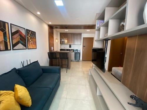a living room with a blue couch and a kitchen at Monte Carmel in Ribeirão Preto