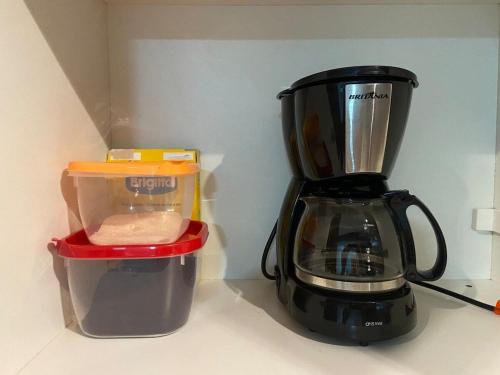 a black blender sitting on a counter next to a container at Monte Carmel in Ribeirão Preto
