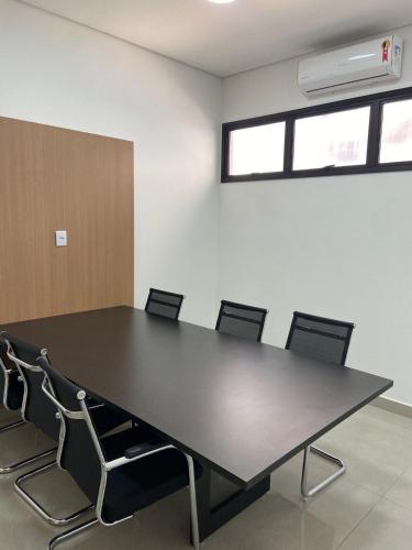 a conference room with a black table and chairs at Monte Carmel in Ribeirão Preto