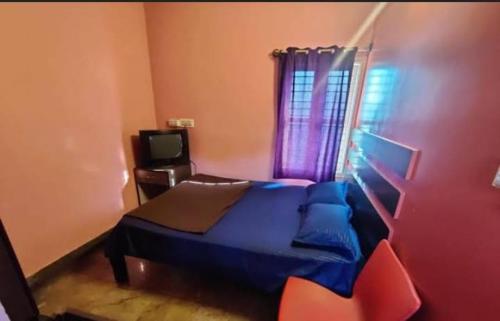 - une chambre avec un lit bleu et une fenêtre dans l'établissement Empire lodge, à Chikmagalur